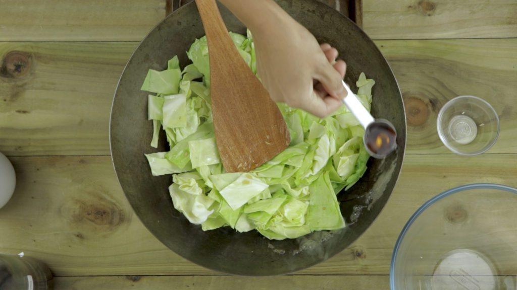 adding fish sauce to the cabbage stir fry