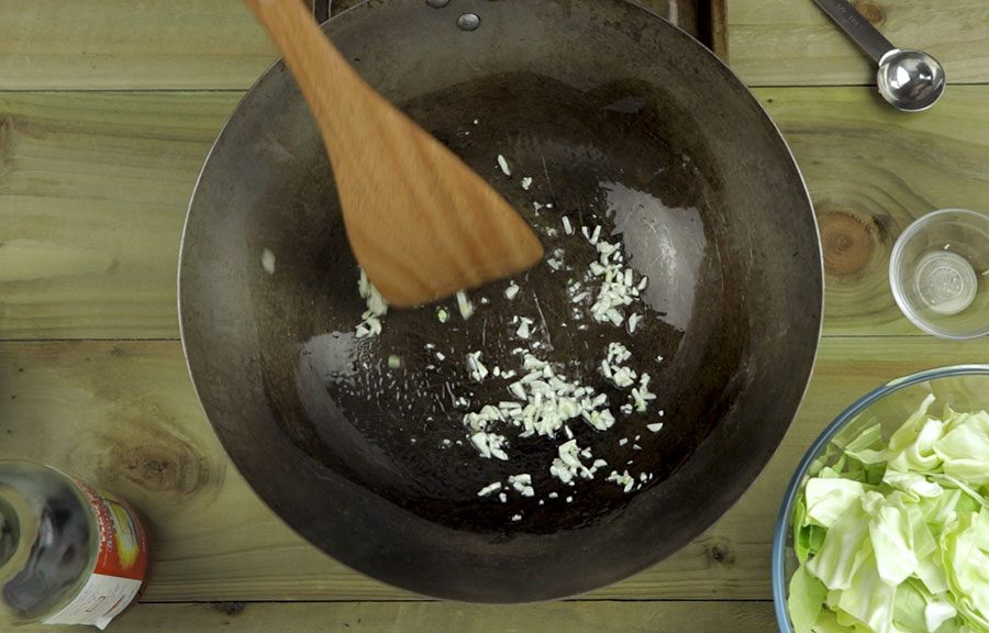 adding garlic to the cabbage stir fry