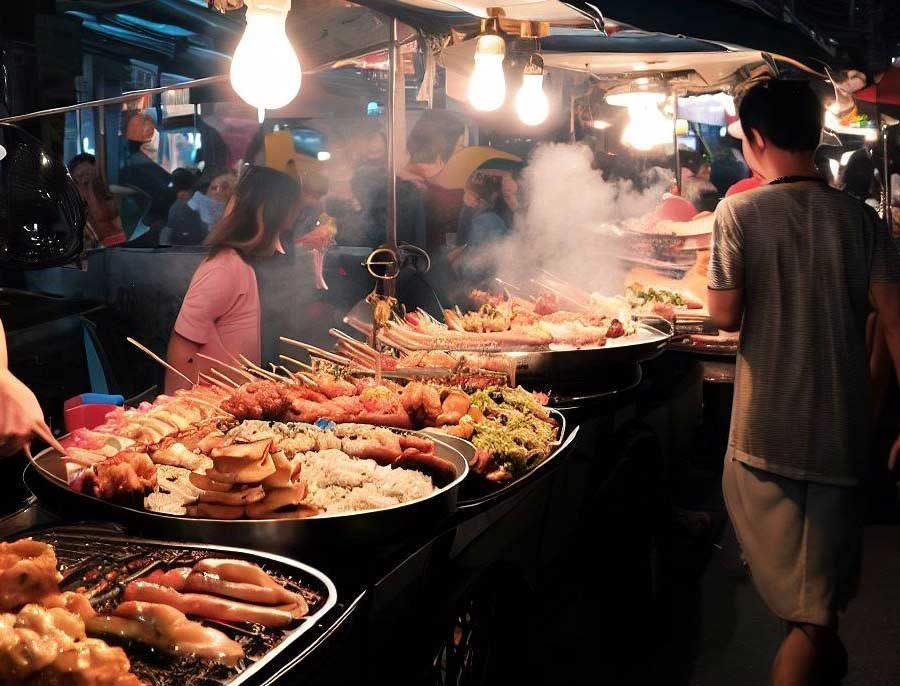 Busy Bangkok street food market with vendors cooking authentic Thai dishes at night